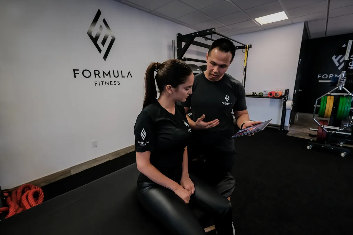 A coach reviewing a tablet with a client at Formula Fitness