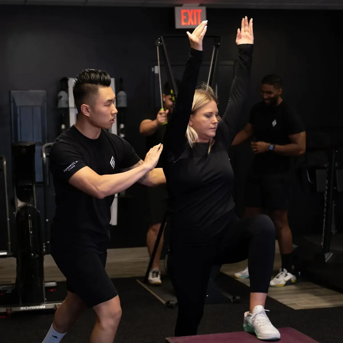 A Formula Fitness coach guiding a client through a one-legged balance exercise
