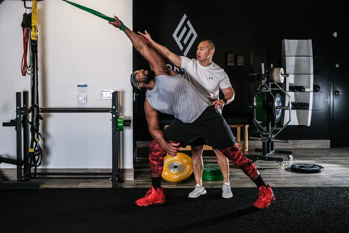 A coach guiding a client through a band-assisted stretch at Formula Fitness